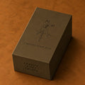 Standard Issue Deck box in olive green with embossed boxer-and-sword illustration, on a tan leather surface